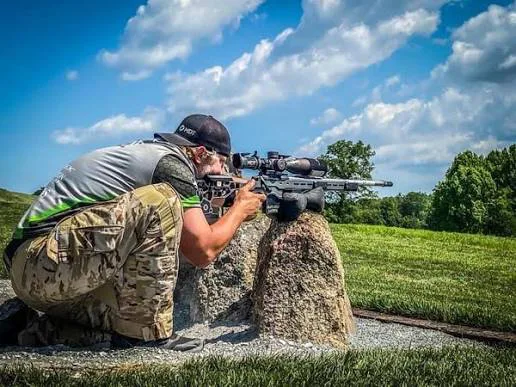 Matt Stiner shooting his rifle off a rock barricade at a match